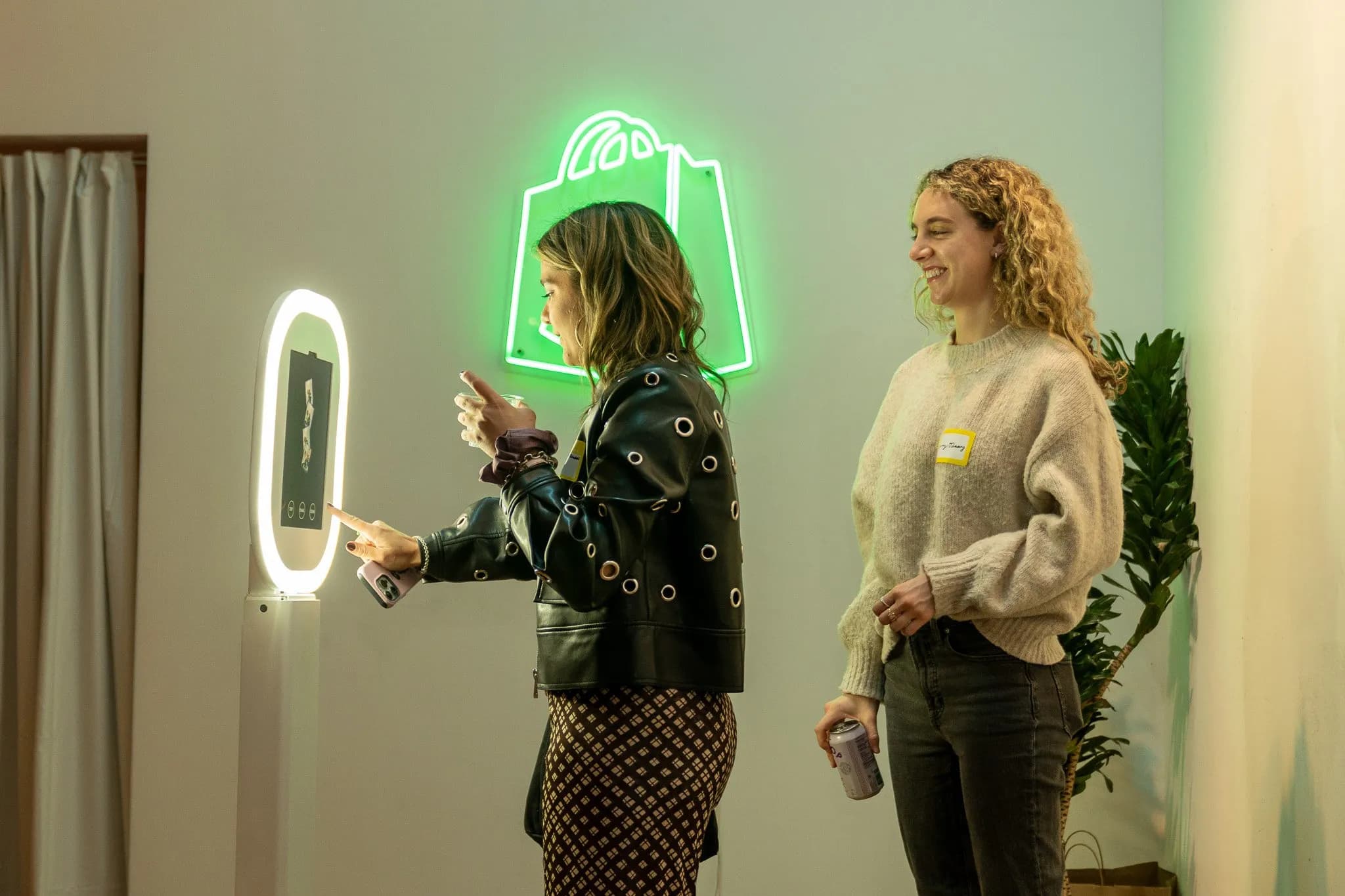 Founders at a Shopify-branded photo booth under a glowing Shopify neon sign