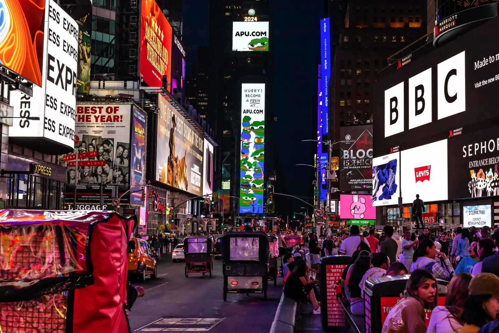 Times Square at night with glowing digital billboards covering both sides of the street