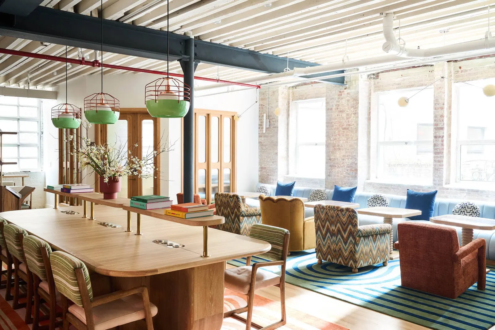 The Malin West Village — communal worktables and lounge seating under green pendant lights